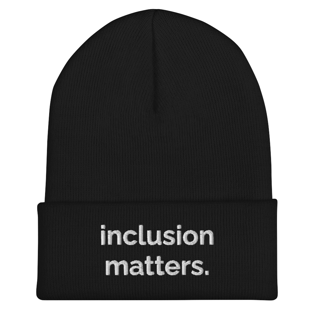A black Inclusion Matters beanie against a plain white background. On the front of the beanie the phrase, 'Inclusion Matters,' is embroidered on it in white sentence case letters over two lines.