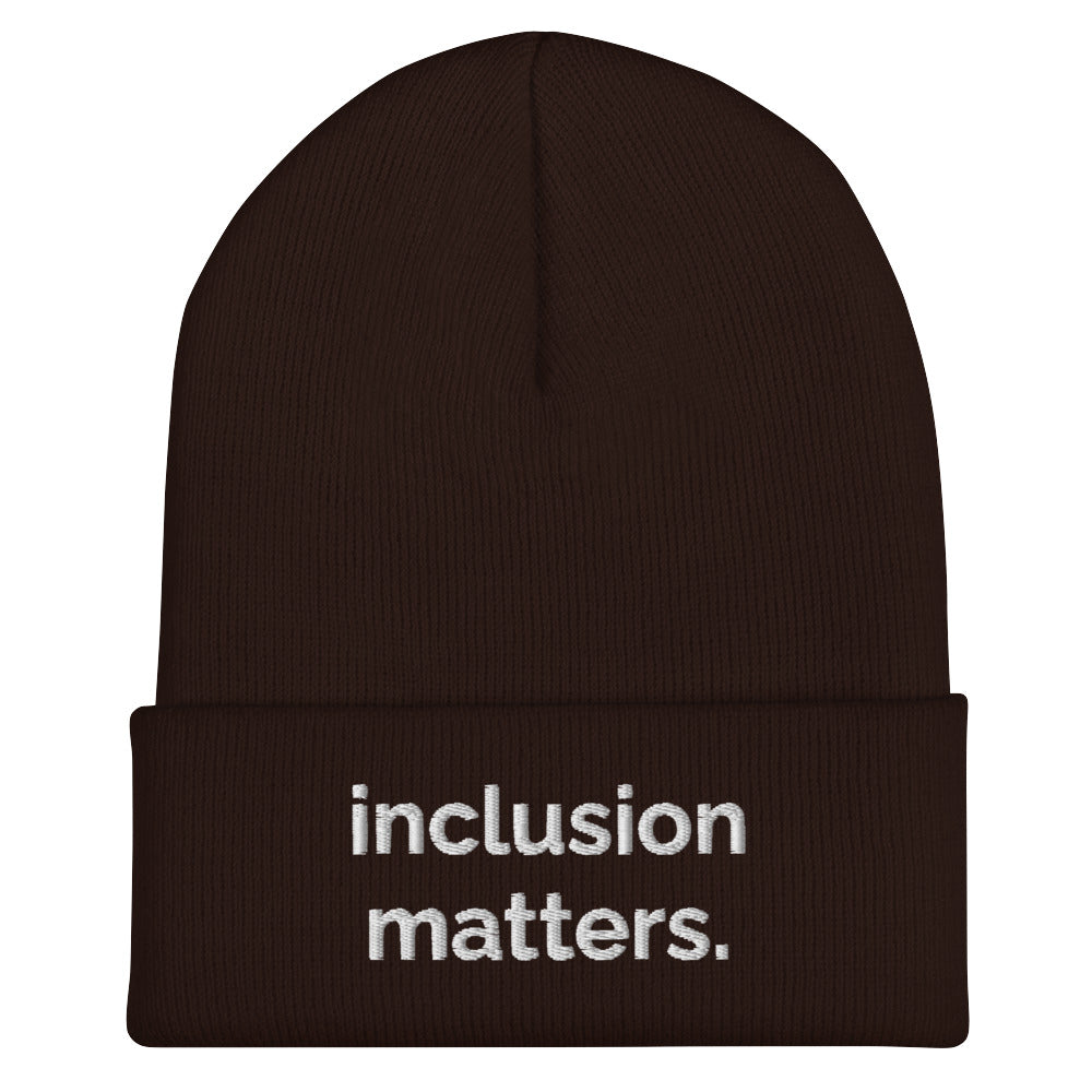 A brown Inclusion Matters beanie against a plain white background. On the front of the beanie the phrase, 'Inclusion Matters,' is embroidered on it in white sentence case letters over two lines.