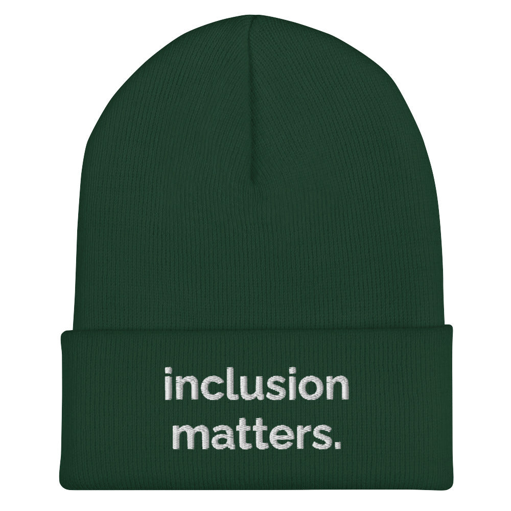 A spruce Inclusion Matters beanie against a plain white background. On the front of the beanie the phrase, 'Inclusion Matters,' is embroidered on it in white sentence case letters over two lines.