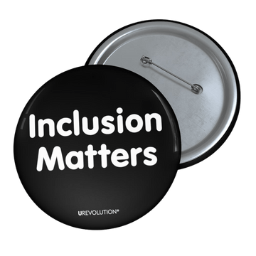A black Inclusion Matters pin button against a plain white background. On the front of the pin button are two words, 'Inclusion Matters.' printed in white sentence case letters over two lines. At the bottom edge of the inclusion badge, beneath the phrase, 'Inclusion Matters,' is the brand name URevolution in small white upper case letters.