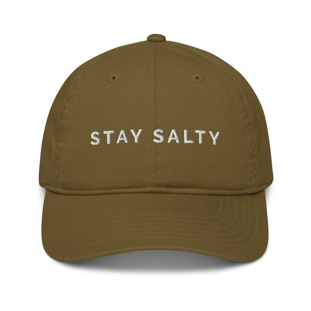A photo of a jungle-khaki-green colored organic Stay Salty cap lying flat against a plain background. On the front panel of the cap the phrase, 'Stay Salty,' is embroidered on it in white upper case letters. 