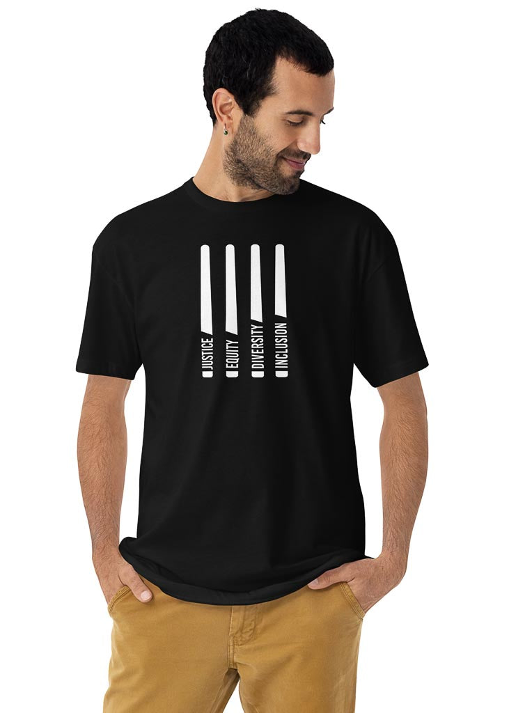This is a photo of a black J.E.D.I. sustainable heavyweight tee. In the middle of the front of the t-shirt, are four white laser swords. At the bottom of each sword representing the handle is one word: Justice Equity Diversity Inclusion. Beneath the swords is the acronym J.E.D.I in white upper case letters. The justice J.E.D.I. shirt is worn by a male model in beige pants.