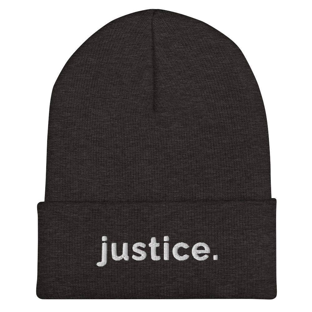 A dark-grey a justice beanie has the word 'justice.' embroidered in white lower case letters on the front of the beanie.