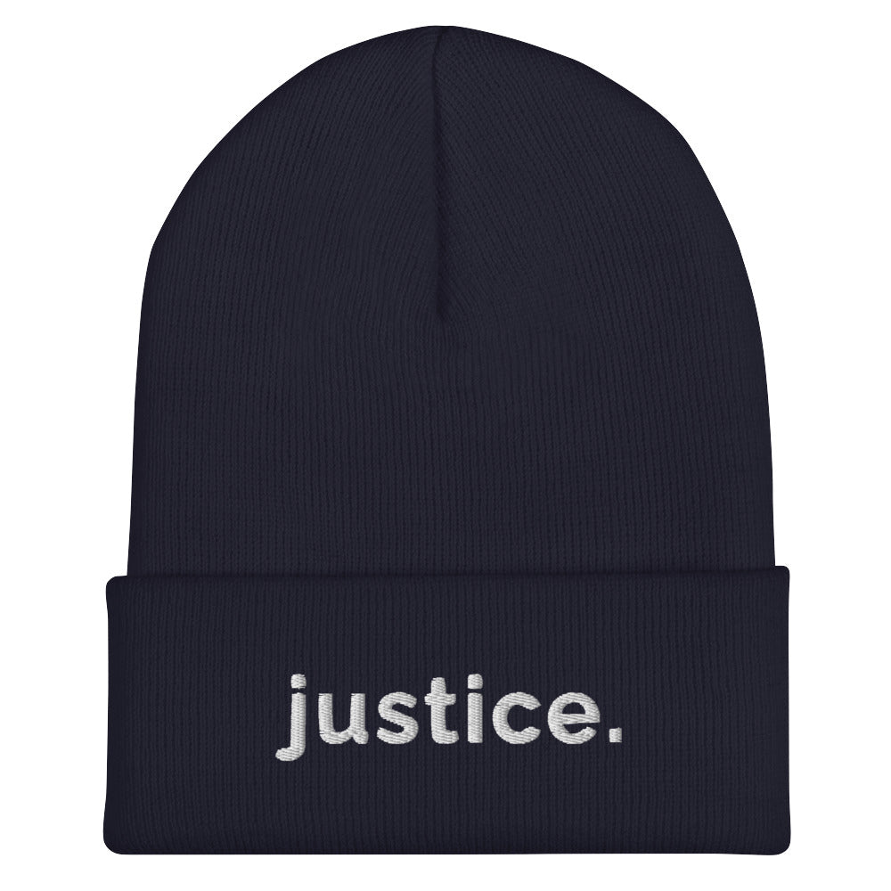 A navy a justice beanie has the word 'justice.' embroidered in white lower case letters on the front of the beanie.