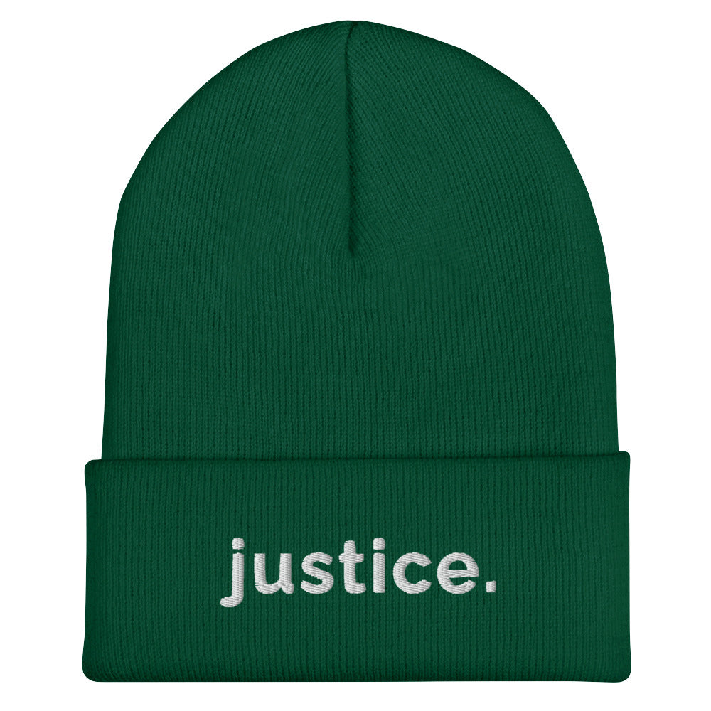 A spruce a justice beanie has the word 'justice.' embroidered in white lower case letters on the front of the beanie.