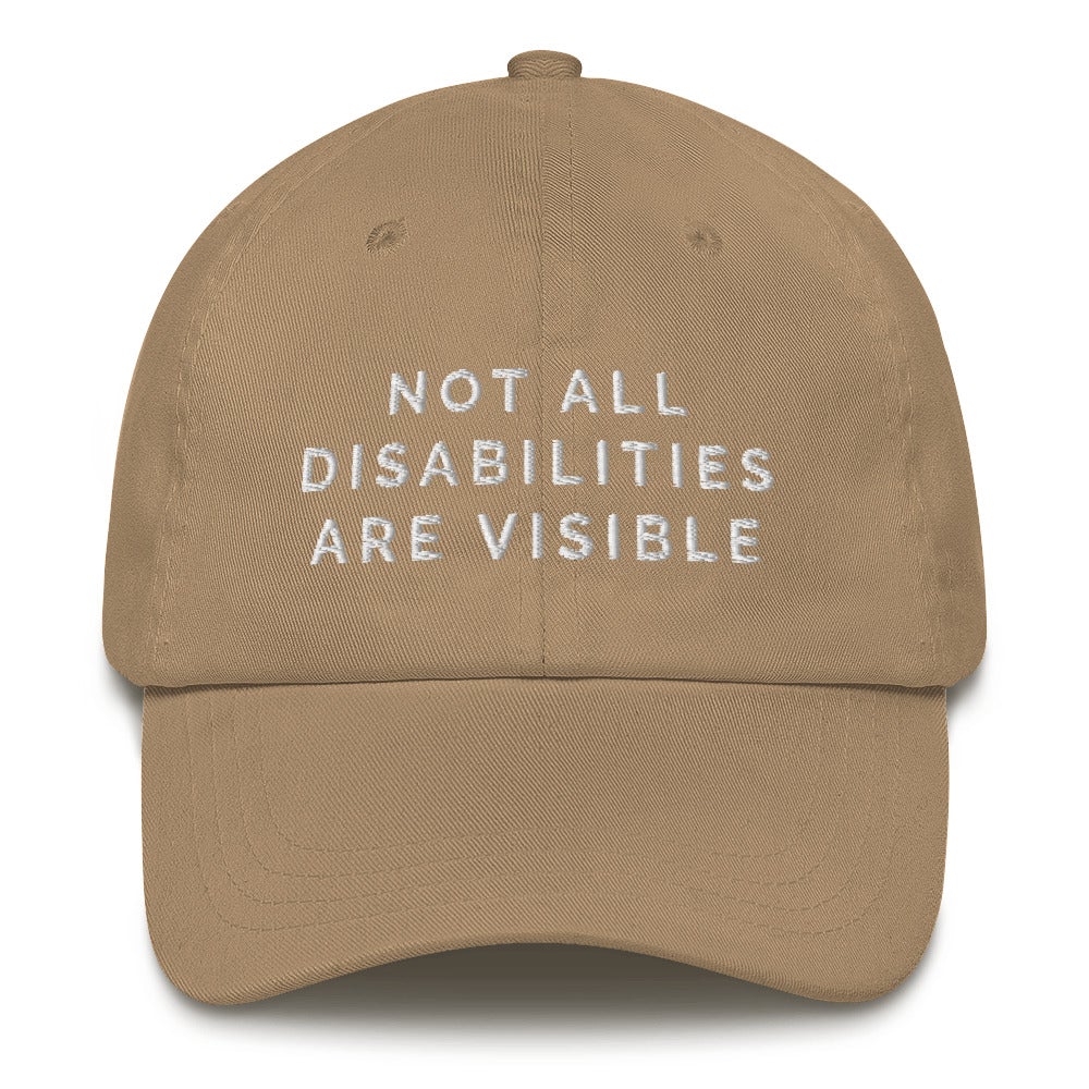 This is a photo of the front of a khaki Not All Disabilities Are Visible Cap. In the middle of the cap, in white embroidered upper case letters, is the phrase "Not All Disabilities Are Visible." The phrase is on three lines: (1) not all, (2) disabilities, (3) are visible.