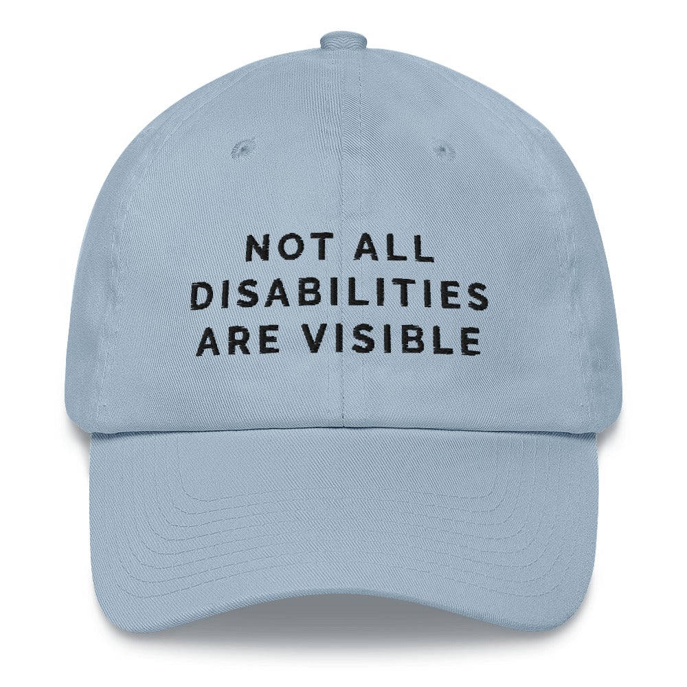 This is a photo of the front of a light-blue-colored Not All Disabilities Are Visible Cap. In the middle of the cap, in black embroidered upper case letters, is the phrase "Not All Disabilities Are Visible." The phrase is on three lines: (1) not all, (2) disabilities, (3) are visible.