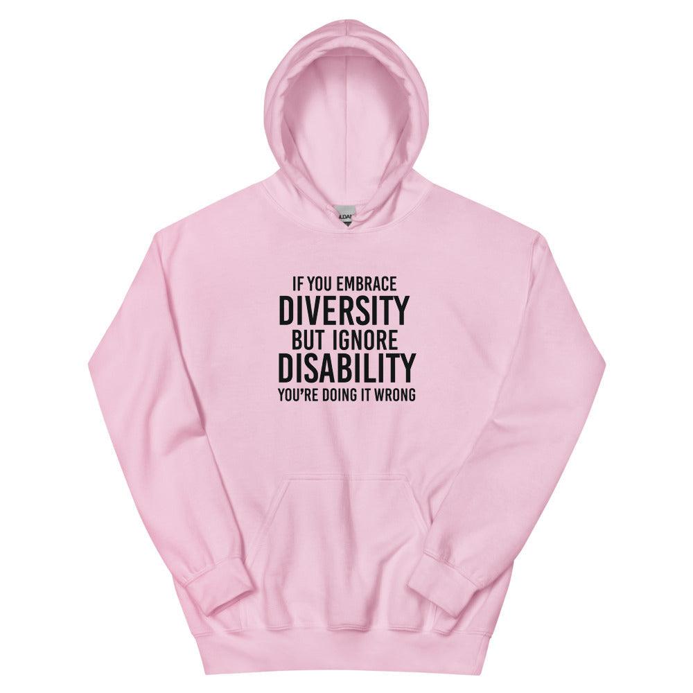 This is a photo of a pink heavy blend embrace diversity hoodie with kangaroo pockets against a plain background. In the middle of the hoodie is a text graphic in bold upper case black letters. The text reads, "If you embrace diversity, but ignore disability, you're doing it wrong."