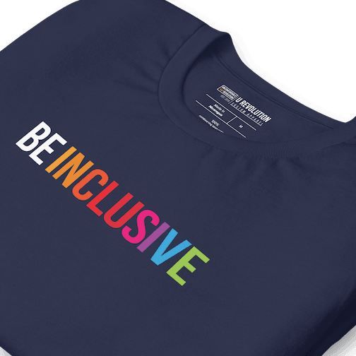 Close up of a navy Be Inclusive t-shirt with text printed in big caps says "BE INCLUSIVE". BE is in white, and INCLUSIVE is in rainbow colors. Both words are in one line across the top of the shirt.