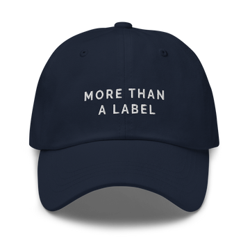 A navy More Than A Label cap. In the middle of the cap is the phrase, 'More Than A Label,' embroidered in white upper case letters.