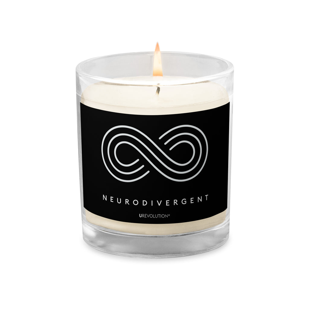 Neurodivergent candle by URevolution. This is a photo of a candle in a glass jar with a black label. In the middle of the black label is a three-ringed infinity symbol with the word 'neurodivergent' in white upper case letters beneath the symbol.  The candle is lit.