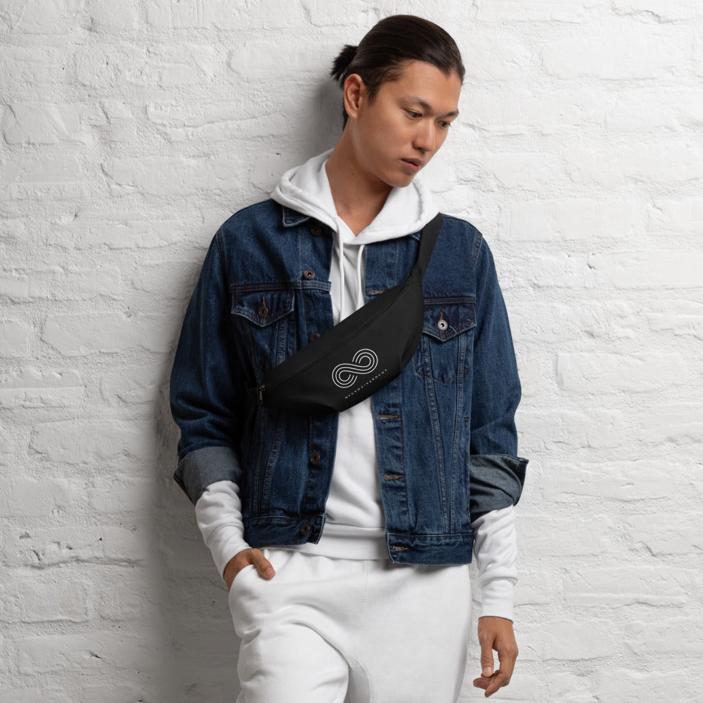 This is a photo of a black Neurodivergent waist bag. On the front of the waist bag is an elegant white infinity symbol consisting of three thin white lines. Just below the symbol is the word Neurodivergent in elegant upper case white letters. A person, wearing a white hoodie tracksuit and blue denim jacket, is wearing the neurodivergent fanny pack across their chest.