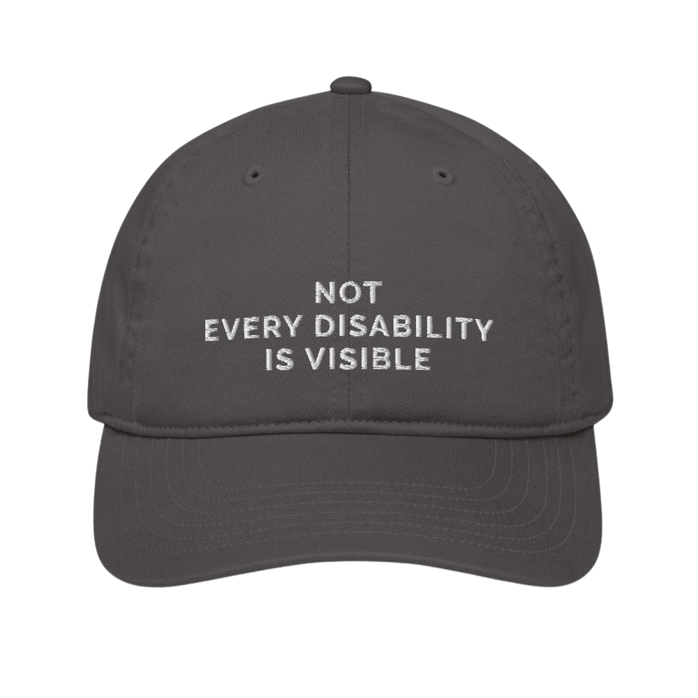 This is a photo of an organic charcoal Not Every Disability Is Visible cap lying flat against a plain background. On the front panel of the cap is the phrase, 'Not Every Disability Is Visible,' embroidered on over three lines in white upper case letters.