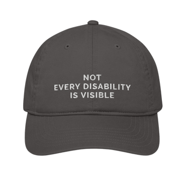 This is a photo of an organic charcoal Not Every Disability Is Visible cap lying flat against a plain background. On the front panel of the cap is the phrase, 'Not Every Disability Is Visible,' embroidered on over three lines in white upper case letters.