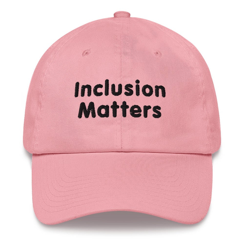 This is a photo of a pink Inclusion Matters Baseball Cap. On the front of the baseball cap above the visor are two words, 'Inclusion Matters.' printed in black sentence case letters over two lines.