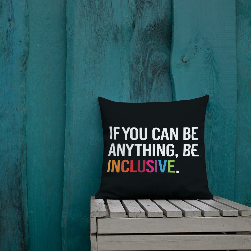 This is an image of a black premium Be Inclusive throw cushion. In the middle of the square throw cushion, the following phrase is printed in white upper case letters, "IF YOU CAN BE ANYTHING, BE INCLUSIVE." The word INCLUSIVE is in rainbow-like colors. 
