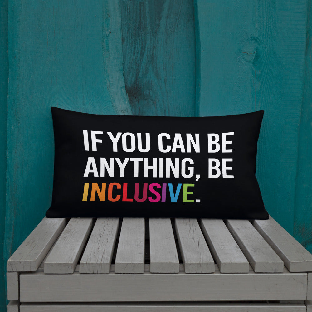 This is an image of a black premium Be Inclusive throw cushion. In the middle of the rectangle throw cushion, the following phrase is printed in white upper case letters, "IF YOU CAN BE ANYTHING, BE INCLUSIVE." The word INCLUSIVE is in rainbow-like colors. 