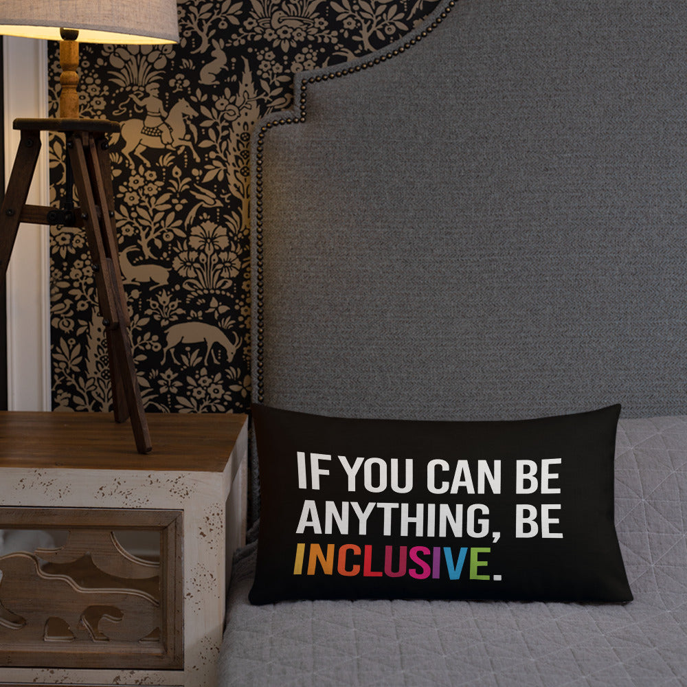 This is an image of a black premium Be Inclusive throw cushion. In the middle of the rectangle throw cushion, the following phrase is printed in white upper case letters, "IF YOU CAN BE ANYTHING, BE INCLUSIVE." The word INCLUSIVE is in rainbow-like colors. 