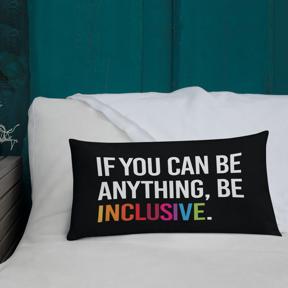 This is an image of a black premium Be Inclusive throw cushion. In the middle of the rectangle throw cushion, the following phrase is printed in white upper case letters, "IF YOU CAN BE ANYTHING, BE INCLUSIVE." The word INCLUSIVE is in rainbow-like colors. 