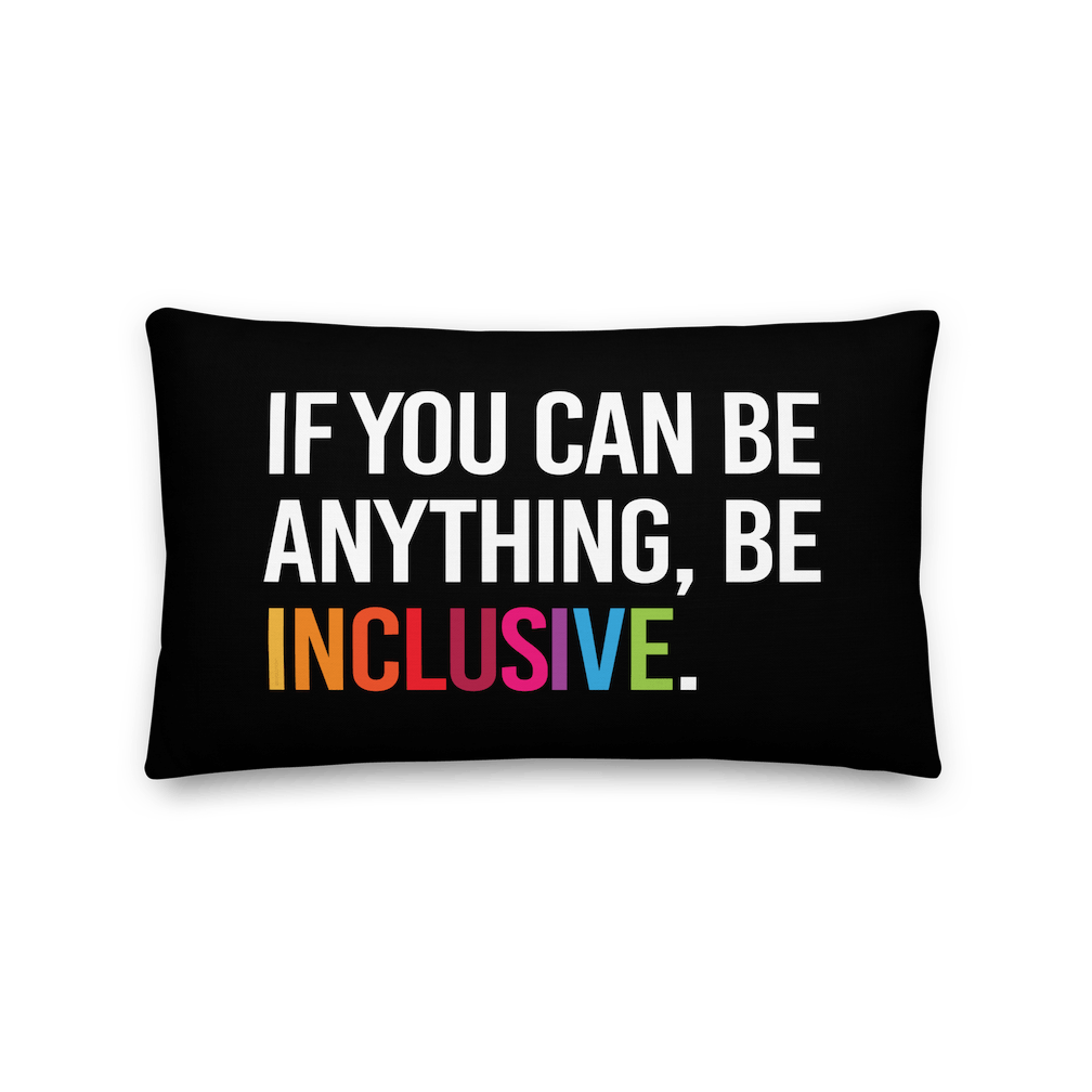 This is an image of a black premium Be Inclusive throw cushion. In the middle of the rectangle throw cushion, the following phrase is printed in white upper case letters, "IF YOU CAN BE ANYTHING, BE INCLUSIVE." The word INCLUSIVE is in rainbow-like colors. 