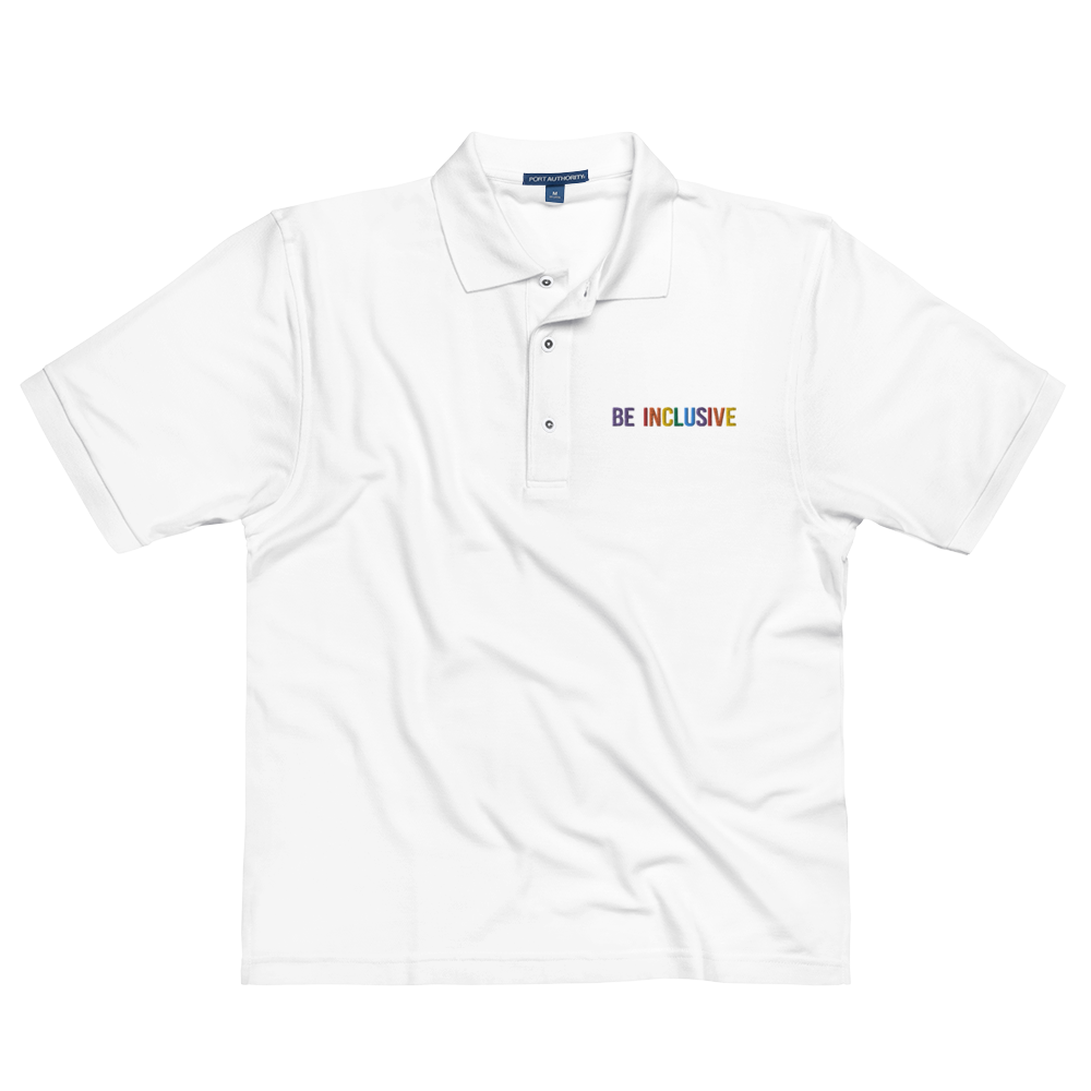 This is a photo of a premium white Rainbow Polo Shirt. On the polo's top right panel is the phrase, Be Inclusive, embroidered in red, orange, yellow, green, indigo, and violet. The word 'be' is only in violet. 