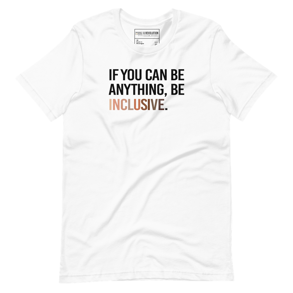 A photo of a white Be Inclusive t-shirt promoting racial diversity. On the front of the inclusive t-shirt is the phrase: "If you can be anything, be inclusive," in black upper case letters.  The text is all black, except the word "Inclusive," which is in different skin colors, with the lightest color on the left and the darkest on the right. 