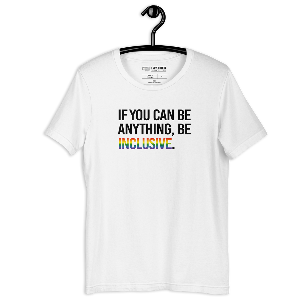 This is a photo of a white Rainbow Be Inclusive Pride Tee. On the front of the inclusive t-shirt is the phrase: "If you can be anything, be inclusive," in black upper case letters. All the text is in black, except "Inclusive," which is in blended upper case rainbow pride colors:  red, orange, yellow, green, indigo, and violet. The pride t-shirt is on a hanger.