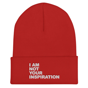 A photo of a red Not Your Inspiration Hypoallergenic Beanie lying flat against a plain background. On the cuff of the beanie the phrase, 'I am not your inspiration,' is embroidered on it over four lines in white upper case letters. Beanie Inspo.