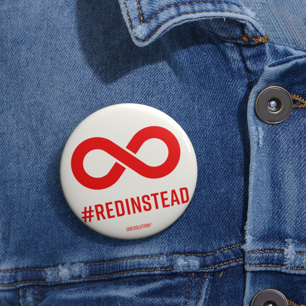 A Red Instead pin button badge. A solid red infinity symbol is in the middle of the soft white pin button. Beneath the symbol is the word #RedInstead printed in bold red upper case letters. .  The 2.25 inch is worn on a faded blue denim jacket.