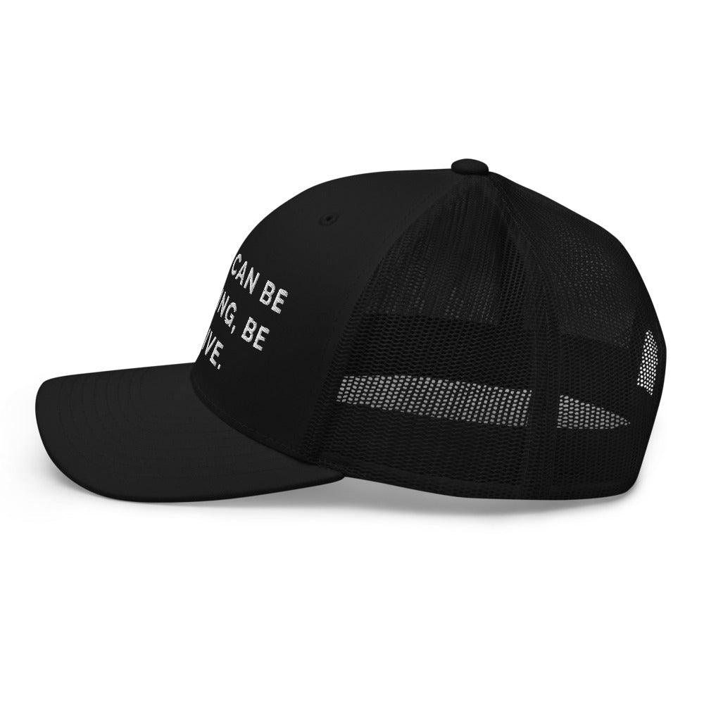 This is a side view of the mesh panels of a Be Anything Be Inclusive Trucker Cap. The cap visor is partially visible. 
