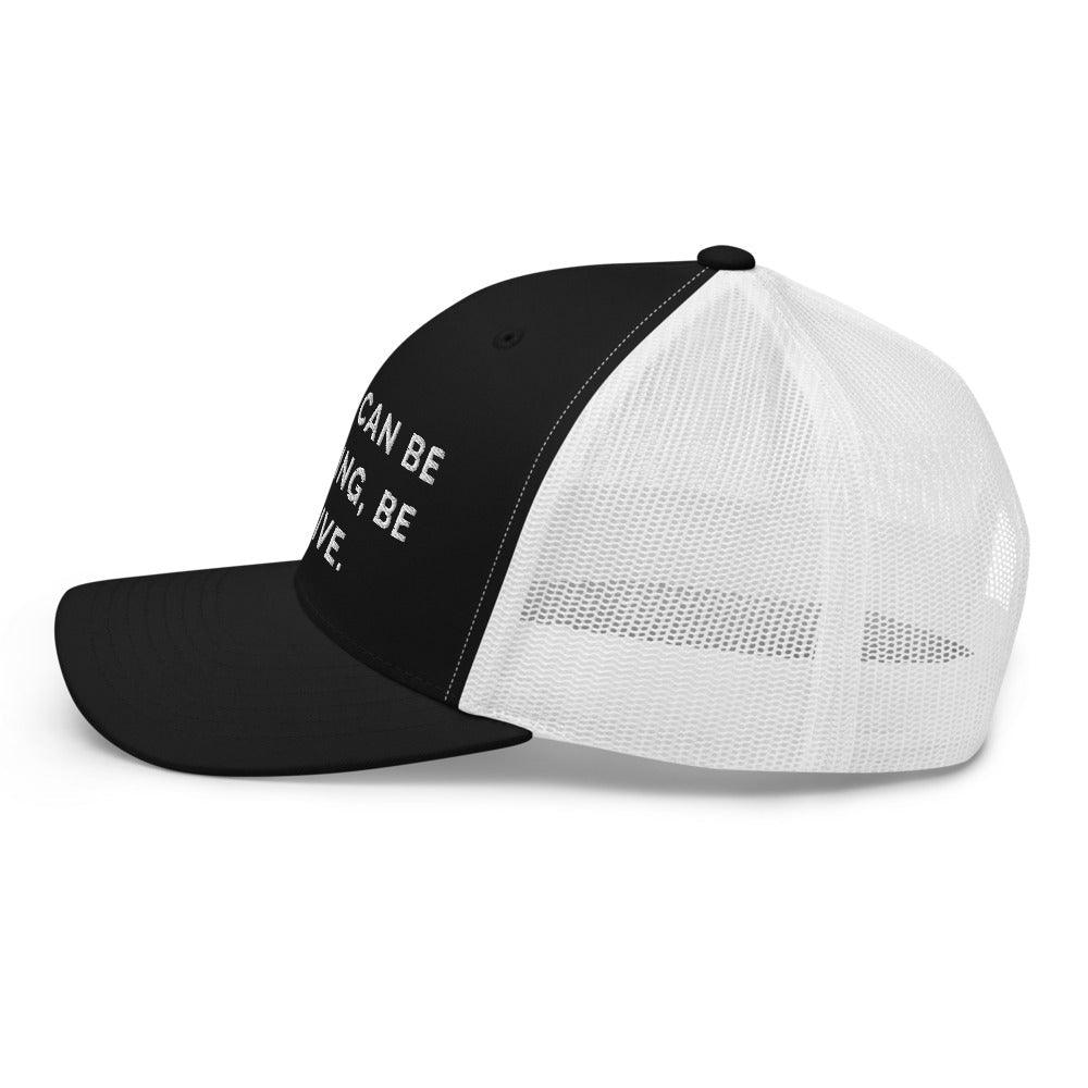 This is a side view of the mesh panels of a Be Anything Be Inclusive Trucker Cap. The cap visor is partially visible. 