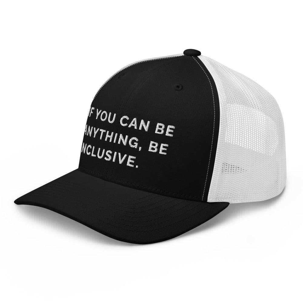 This is a photo of a black and white Be Anything Be Inclusive Trucker Cap. In the middle of the cap's black front panel is the phrase, embroidered in white upper case letters, "If you can be anything, be inclusive." 