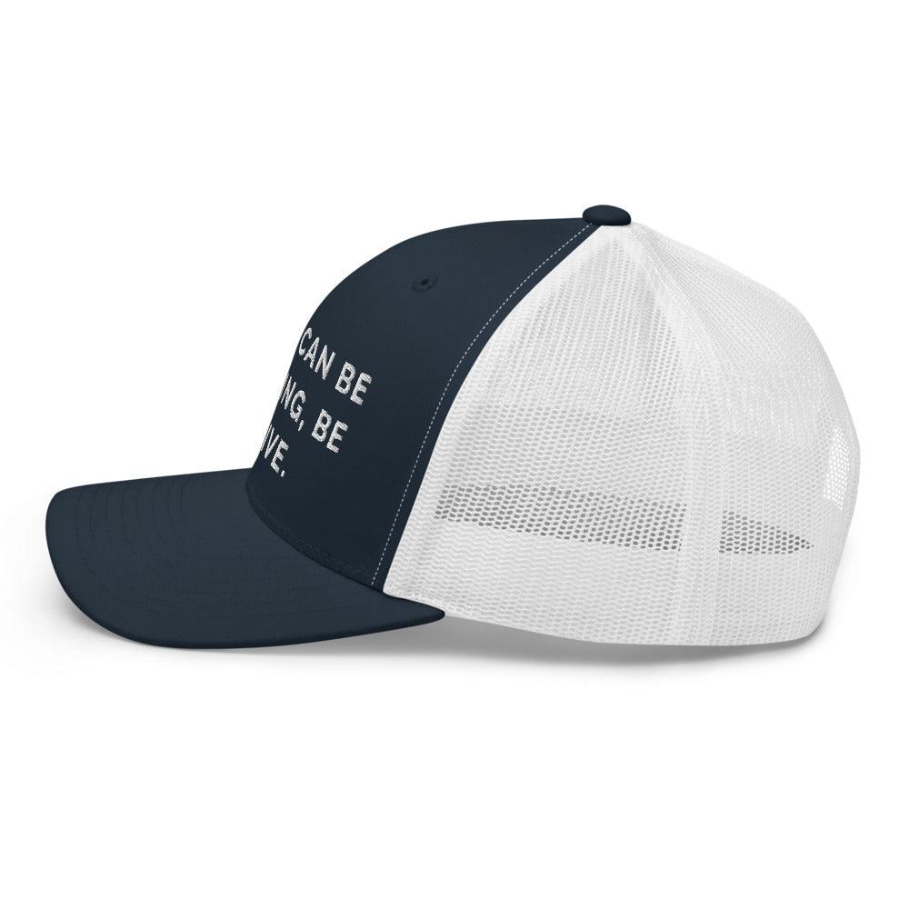 This is a side view of the mesh panels of a Be Anything Be Inclusive Trucker Cap. The cap visor is partially visible. 