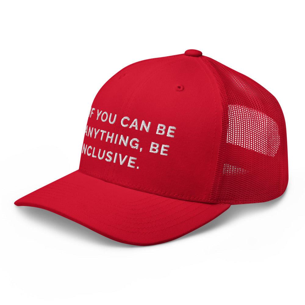 This is a photo of a red Be Anything Be Inclusive Trucker Cap. In the middle of the cap's front panel is the phrase, embroidered in white upper case letters, "If you can be anything, be inclusive." 
