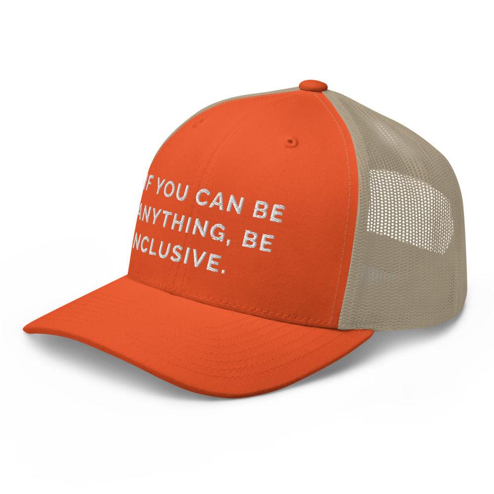This is a photo of a rustic orange khaki Be Anything Be Inclusive Trucker Cap. In the middle of the cap's orange front panel is the phrase, embroidered in white upper case letters, "If you can be anything, be inclusive." 