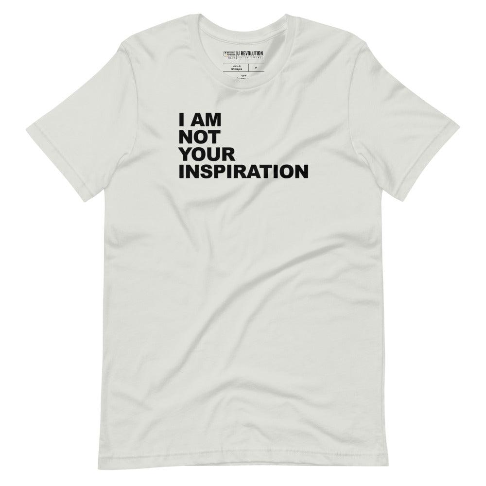 This is a silver 'I Am Not Your Inspiration" t-shirt. On the top third of the inspiration shirt is the phrase, "I am not your inspiration," printed over four lines in black upper case letters.