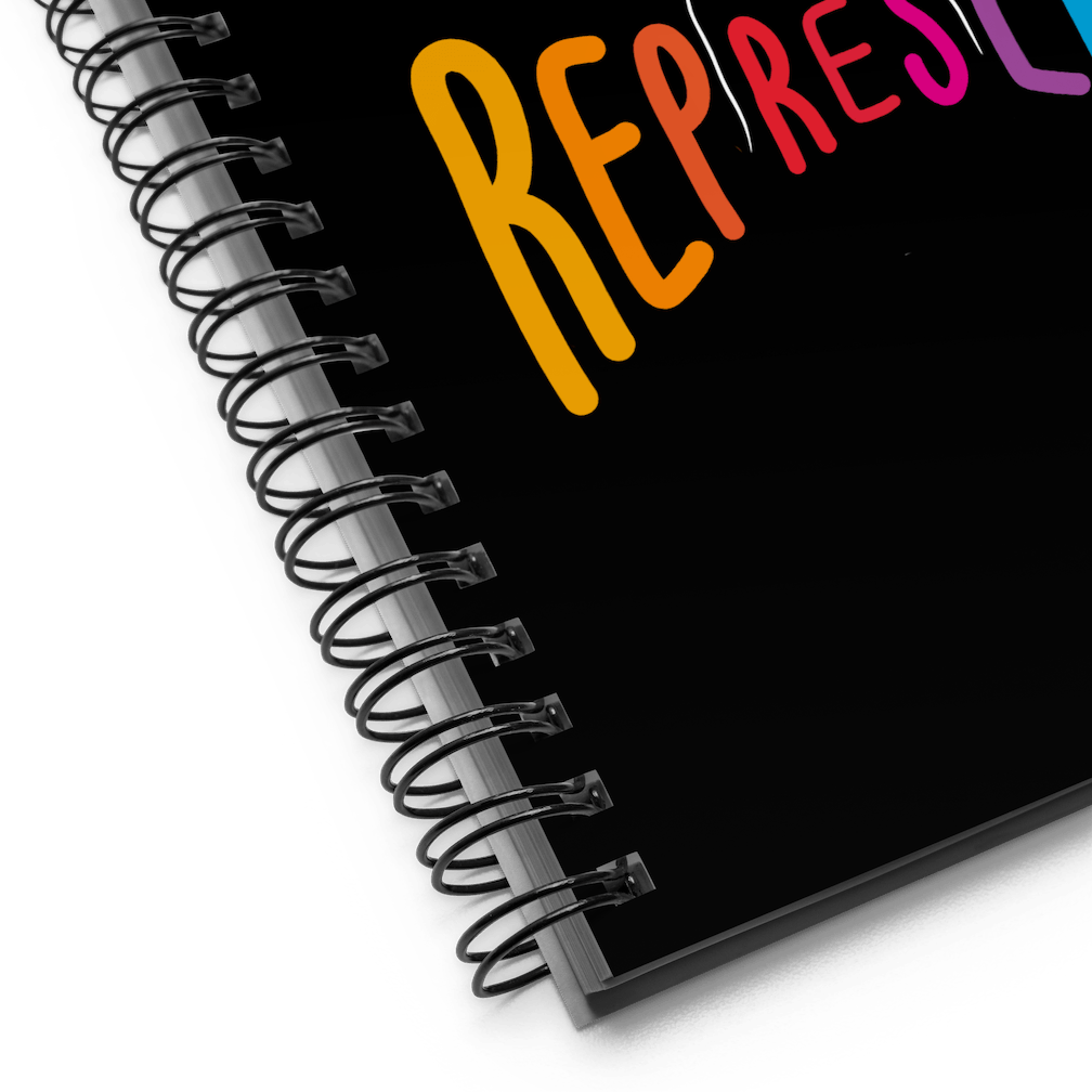 This is a close up of the Represent notebook showing the black metal binding and part of the word Represent.