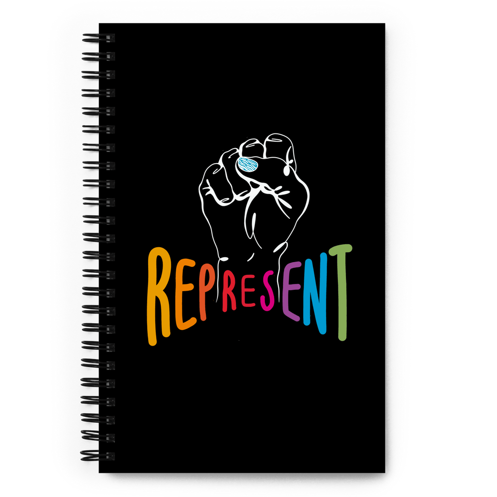 This is a photo of spiral black Represent notebook. In the center of the notebook is a white drawing of a raised clenched fist, with the handwritten word "represent," written in upper case rainbow colors beneath the fist.