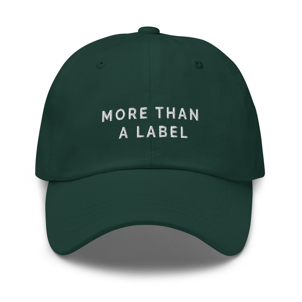 A spruce More Than A Label cap. In the middle of the cap is the phrase, 'More Than A Label,' embroidered in white upper case letters.