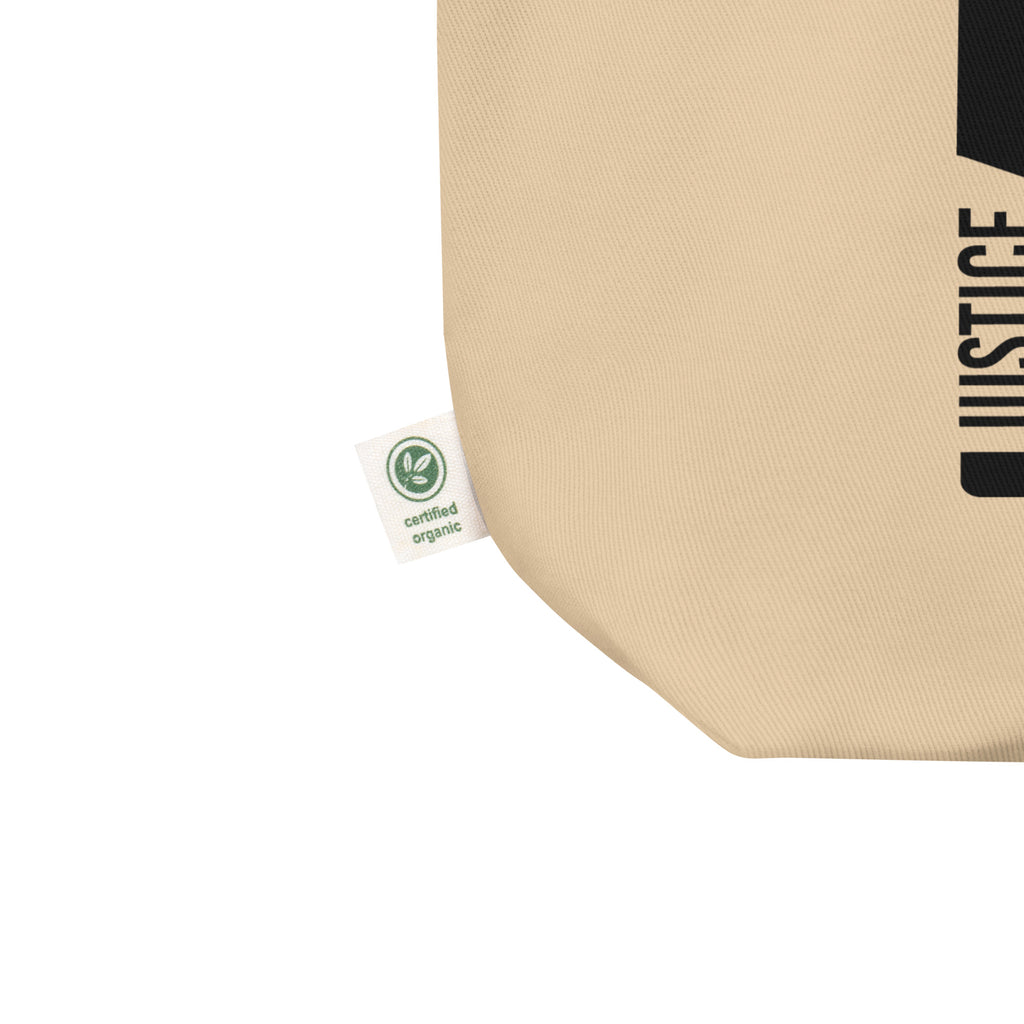 This is a natural Justice Equity Diversity Inclusion organic tote bag. Four black laser swords are placed vertically in the middle of the tote, similar to a flag. On the left-hand side of each sword, in the place of the handle, is one word: Justice Equity Diversity Inclusion.