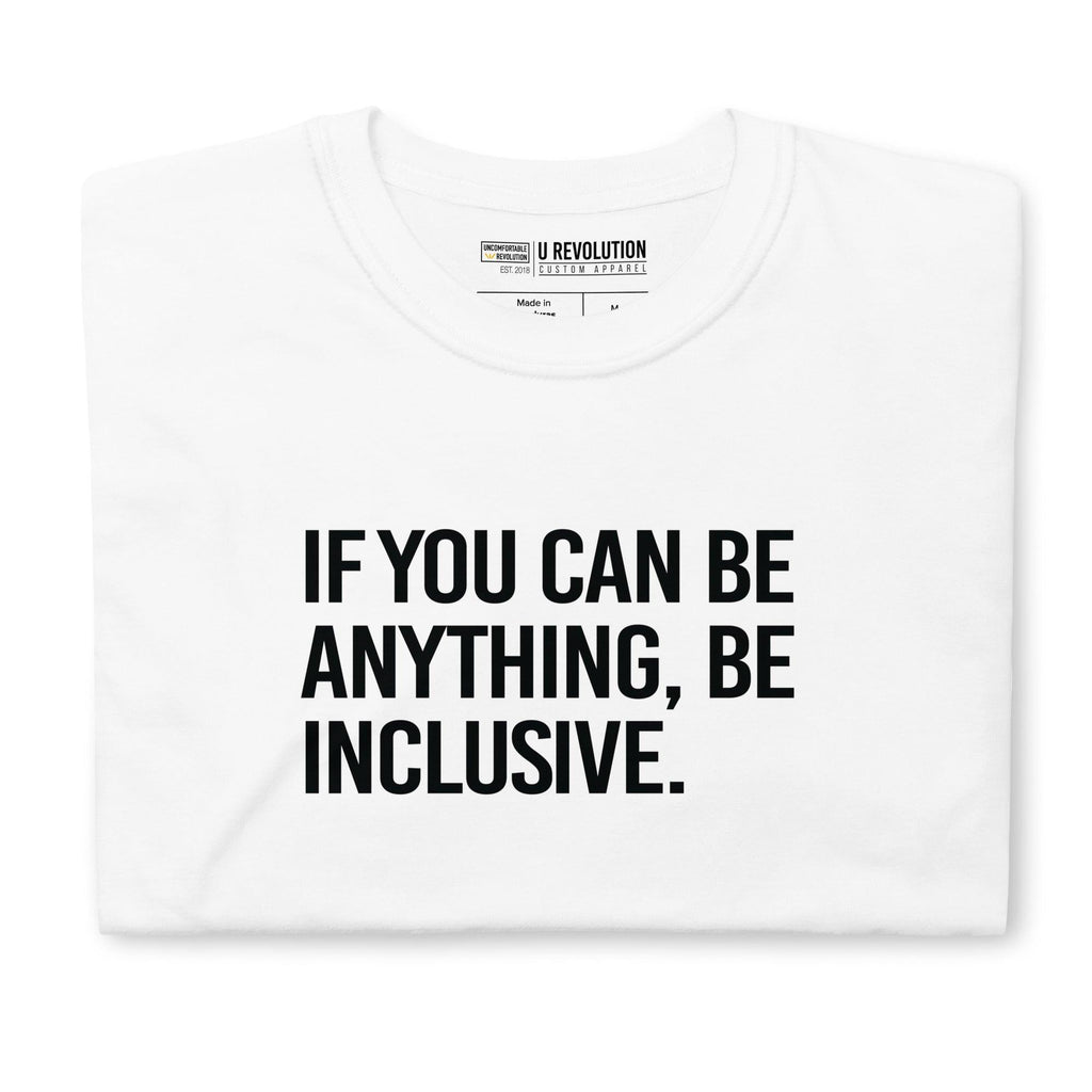 This is a photo of a white Be Inclusive White Basic Tee. On the front of the t-shirt, the phrase, 'If you can be anything, be inclusive,' is printed in black capital letters. The tee is folded.