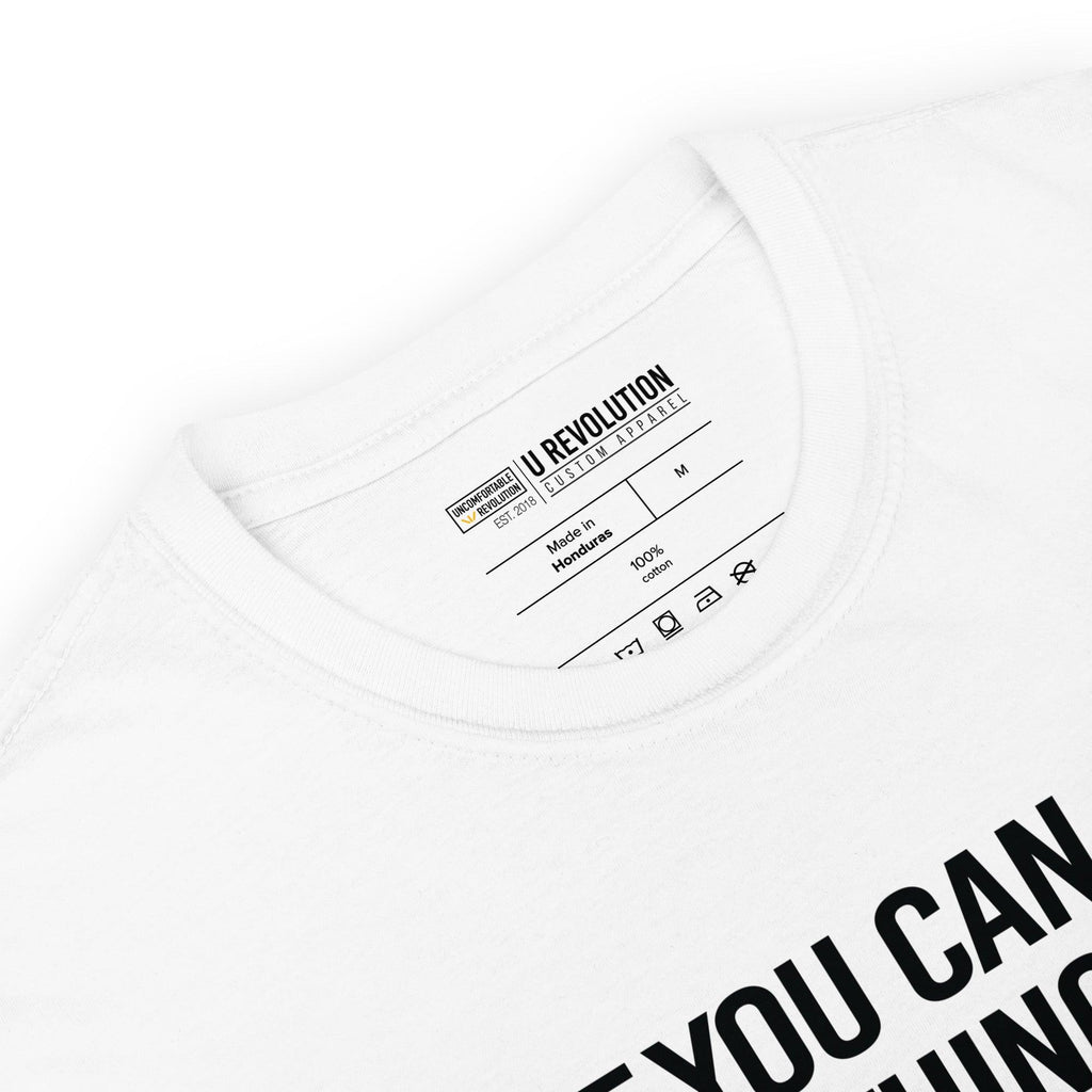 This is a photo of a white Be Inclusive White Basic Tee. On the front of the t-shirt, the phrase, 'If you can be anything, be inclusive,' is printed in black capital letters. You can see the URevolution inside t-shirt label, including care instructions.
