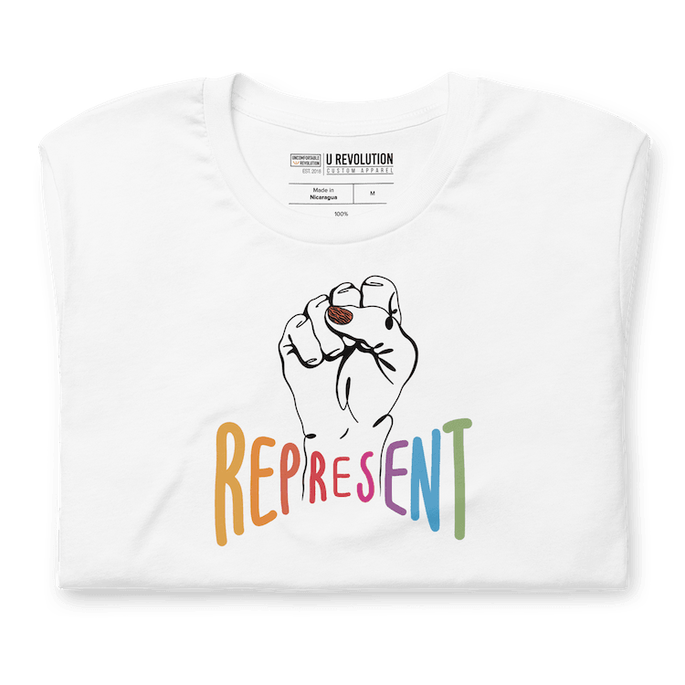 Folded white represent t-shirt. In the middle of the represent shirt is a black line drawing of a raised clenched fist, with the handwritten word "represent," written in upper case rainbow colors.