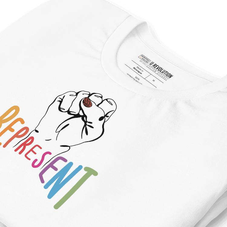 Photo of white Represent Tee. In the middle of the represent tee is a black line drawing of a raised clenched fist, with the handwritten word “represent,” written in upper case rainbow colors.