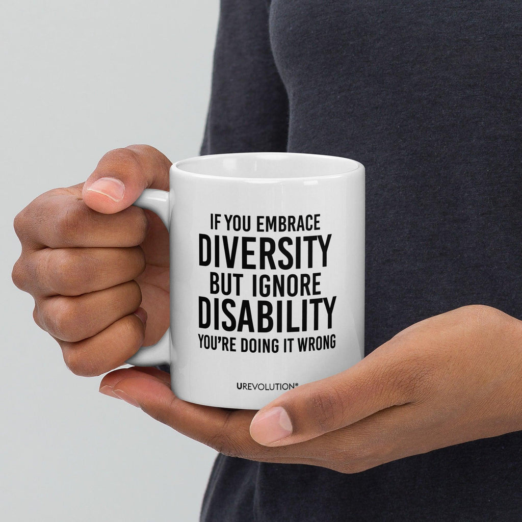 Photo of a white embrace diversity mug. The embrace diversity mug has a phrase printed in black in upper case letters: "If you embrace diversity but ignore disability, you're doing it wrong." The phrase takes up ¾ of the front side of the mug.
