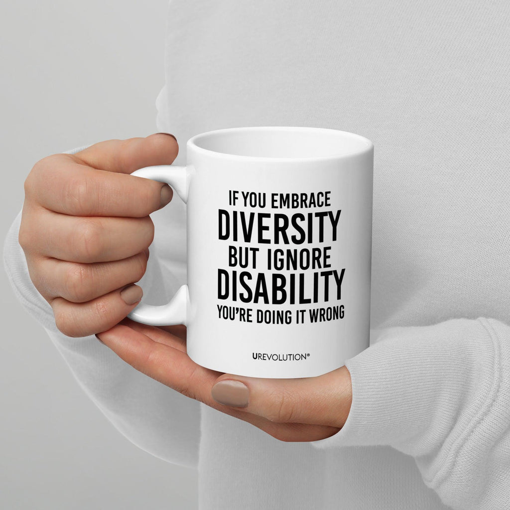 Photo of a white embrace diversity mug. The embrace diversity mug has a phrase printed in black in upper case letters: "If you embrace diversity but ignore disability, you're doing it wrong." The phrase takes up ¾ of the front side of the mug.