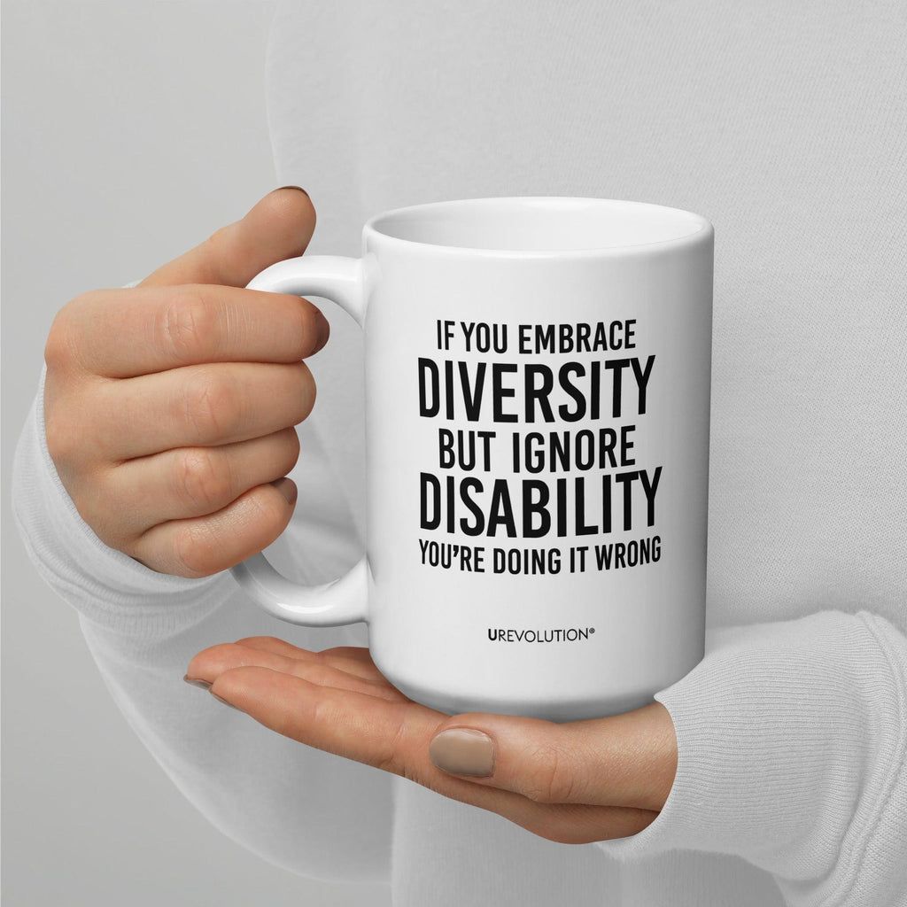 Photo of a white embrace diversity mug. The embrace diversity mug has a phrase printed in black in upper case letters: "If you embrace diversity but ignore disability, you're doing it wrong." The phrase takes up ¾ of the front side of the mug.