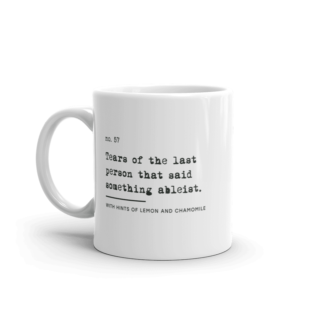 The ableist tears mug is white, with black text that reads: "no. 57. Tears of the last person that said something ableist. With hints of lemon and chamomile." 