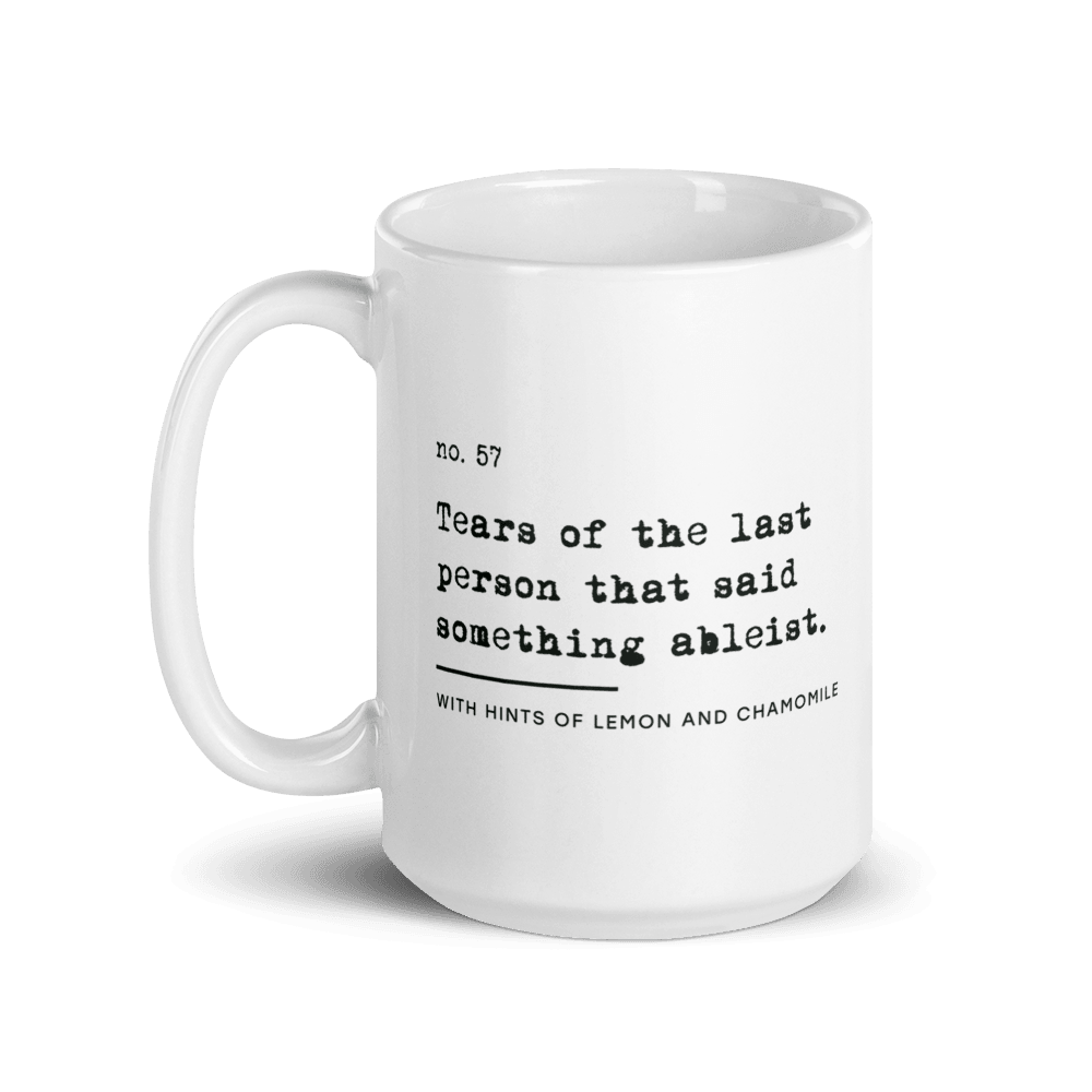 The ableist tears mug is white, with black text that reads: "no. 57. Tears of the last person that said something ableist. With hints of lemon and chamomile." 