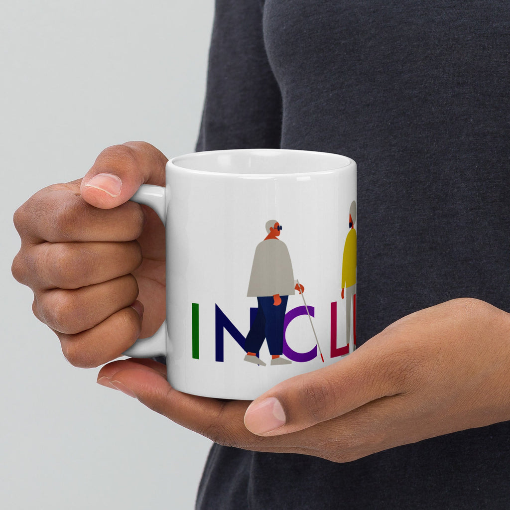 This is a photo of a white inclusion mug with URevolution's Inclusion icon on the side. The word INCLUSION is written in all caps in rainbow colors. Among the letters are four characters: one plus-sized person with glasses and a cane, one person with one arm wearing a turban, one person with long hair and a prosthetic leg, and one person with an afro, seated in a wheelchair.